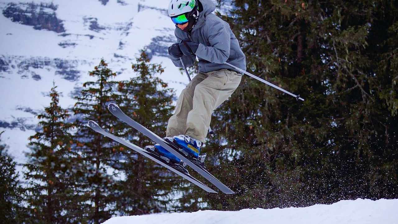 Skier mid-jump against snowy mountains — adventure sports travel insurance and what's excluded