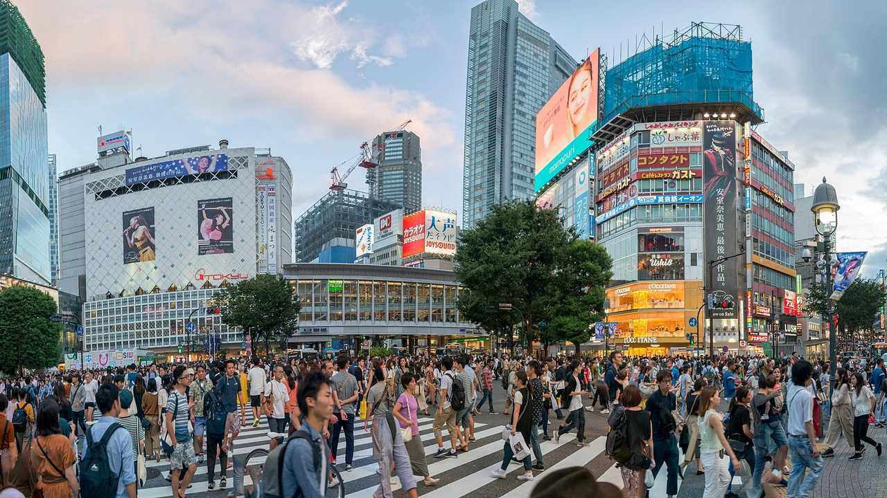 Crowds crossing at the Shibuya scramble crossing in Tokyo beneath large video screens