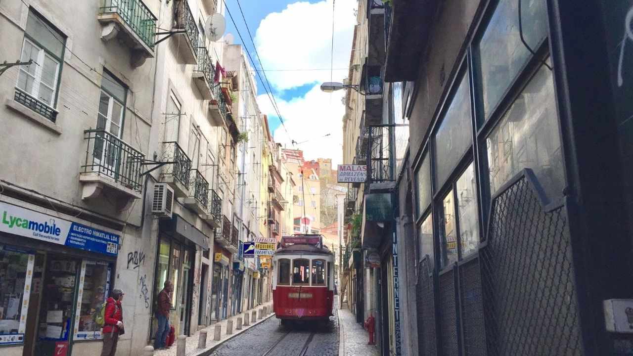 Yellow Tram 28 climbing a narrow street in Alfama, Lisbon, Portugal